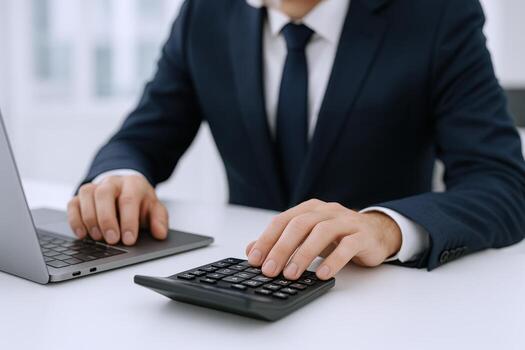 Businessman Calculating Finances with Laptop and Calculator, Focus on Hands and Device at the Desk photo