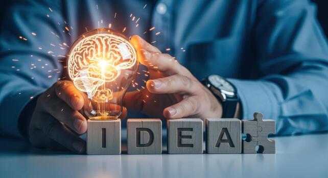 Creative Idea Generation Concept Person Holding Lightbulb with Brain Illustration Over Wooden Blocks Spelling IDEA photo