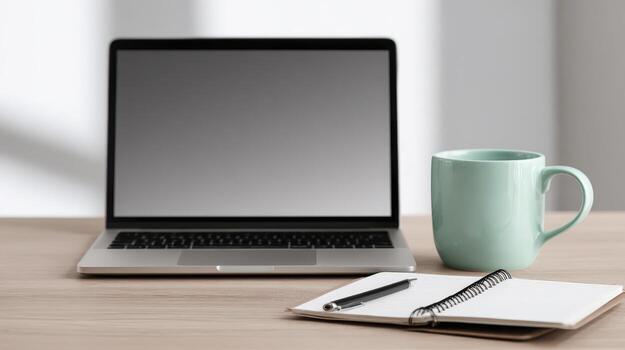 Laptop with Notebook and Coffee Mug on a Desk in a Brightly Lit Work Environment photo