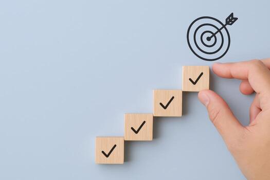 Goal achievement steps depicted by wooden blocks and a hand pointing toward the final target photo