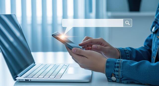 Online Information Search Person Using Mobile Phone with Search Bar Overlay, Laptop Computer Visible photo