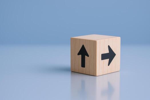 Wooden Cube with Arrows Pointing Up and Right, Representing Direction, Choice, and Strategy on Blue Background photo