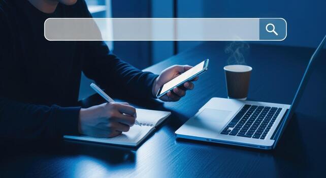 Person working at desk with a smartphone, laptop, and notebook, with search bar overlay, in a blue tone photo