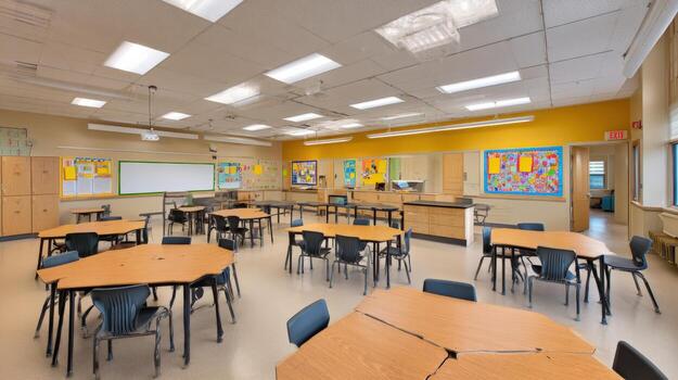 Brightly Lit Modern Classroom Interior Design Featuring Tables, Chairs, and Educational Display Boards for a Positive Learning Space photo