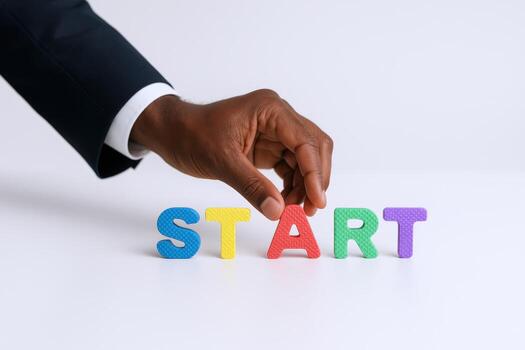 African American Hand Arranges Colorful Foam Letters Spelling Start on White Background, Emphasizing Initiative photo