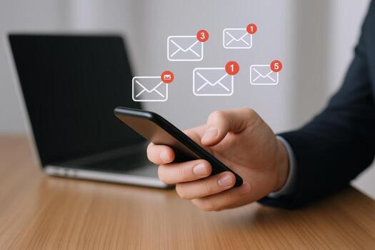 Man Holding Smartphone Checking Email Notifications with Laptop in the Background, Communication and Connectivity photo