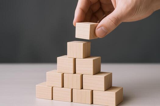 Building Blocks of Success Hand Placing Wooden Cube on Top of Pyramid Structure photo