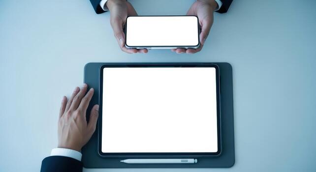 Digital Collaboration Overhead View of Business Professionals Sharing Information on Tablet and Smartphone with Blank Screens photo