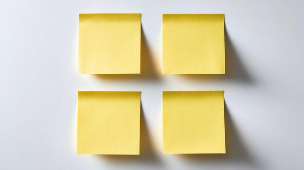 Four Yellow Sticky Notes Arranged on a White Surface, Ready for Messages and Organization photo