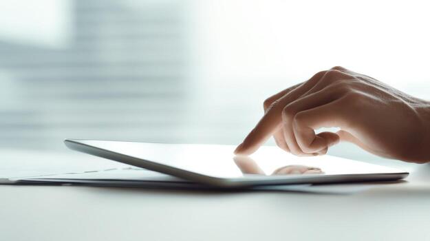 Close-up of hand touching digital tablet screen, emphasizing technology, communication, and modern lifestyle in a bright workspace photo
