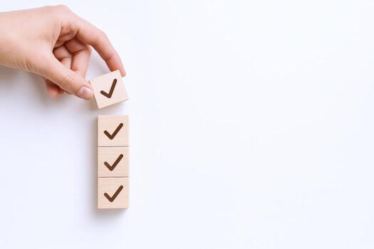 Confirmation with Check Marks Hand Placing Wooden Block on Top of Checklist Stack photo
