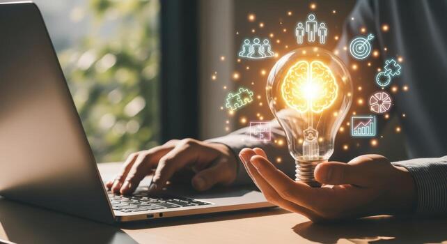 Innovative Business Strategies Person Holding Lightbulb with Brain Symbol and Teamwork Icons while Using Laptop photo