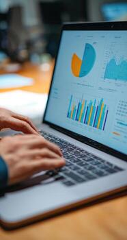 A person is typing on a laptop with graphs on it photo