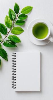 Green tea and notebook on white wooden table top view photo