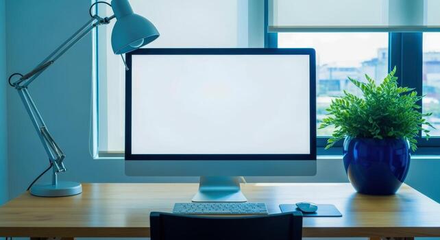 Clean Workspace Mockup Featuring a Blank Computer Screen, Desk Lamp, and Green Plant, Perfect for Presentations photo