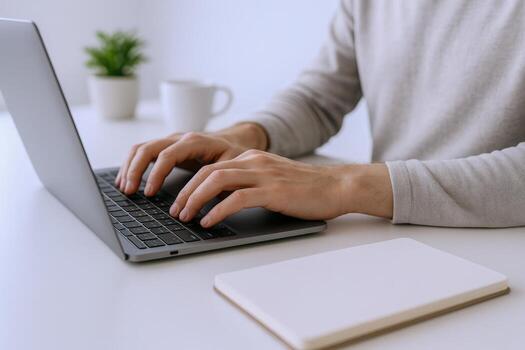 de cerca de manos mecanografía en un ordenador portátil computadora en un brillante, limpiar espacio de trabajo foto