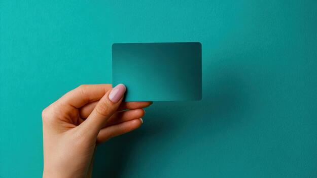 Hand holding turquoise blank card against a matching background, perfect for showcasing text and design mockups photo