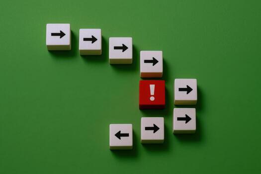 Disruption Concept Red Block with Exclamation Mark Disrupting Arrow Flow on Green Background photo