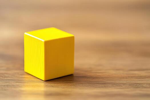 Bright yellow wooden block resting on a smooth brown wooden surface photo