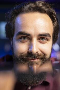Close up shot of smiling content creator holding smartphone in front if camera while filming review for online channel. Portrait of happy man showcasing mobile phone display photo