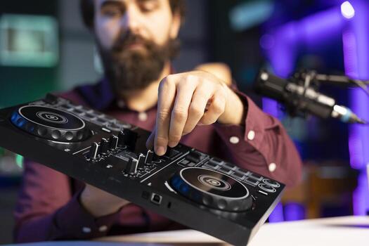 Close up shot of artist filming DJ mixing tutorial, showing examples of sampling on sound controller to audience. Focus on modern musical equipment presented by internet star in blurry background photo