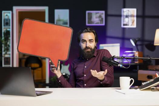 Influencer filming sponsored content, holding empty copy space sign, following script while talking to viewers. Internet star using red cardboard bubble speech cutout to do influencer marketing photo