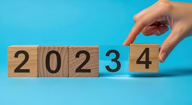 Wooden Blocks Changing from 2023 to 2024 on Blue Background Symbolizing the New Year photo