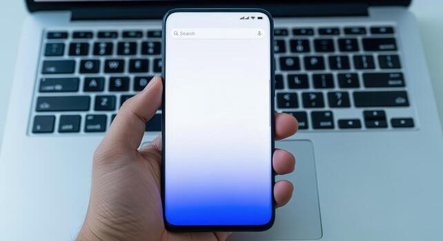 Person holding smartphone with blank screen over laptop, showcasing application or website interface for business or personal use photo