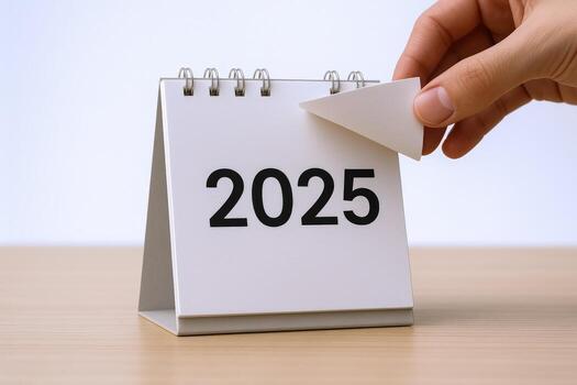 Desk Calendar Displaying 2025 with Hand Turning Page, Foresight and Planning for New Year photo