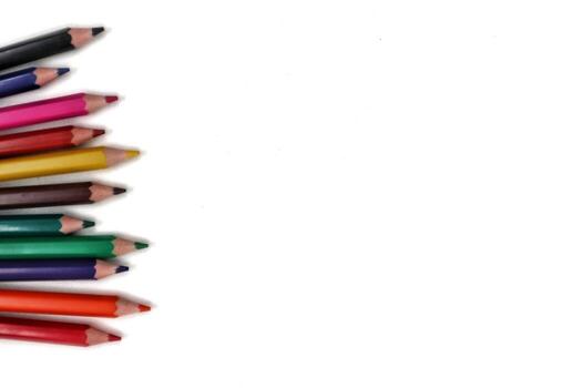 An assortment of colorful pencils aligned along the left edge of the frame, leaving ample space on the right for text or other graphic elements. photo