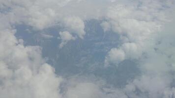 se från flygplan fönster på berg intervall täckt förbi moln under flyg video