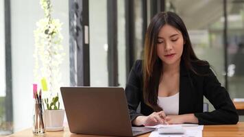 kvinna revisor arbetssätt använder sig av kalkylator och bärbar dator, grafer statistik på enhet skärm. göra betalningar uppkopplad genom säkra Bank systemet, analysera företag kostnader Beräkna kostnader begrepp video