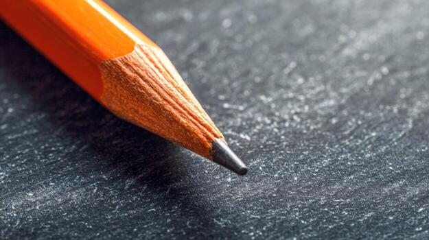 Close-Up of an Orange Graphite Pencil on Textured Dark Background with Graphite Lead Visible photo