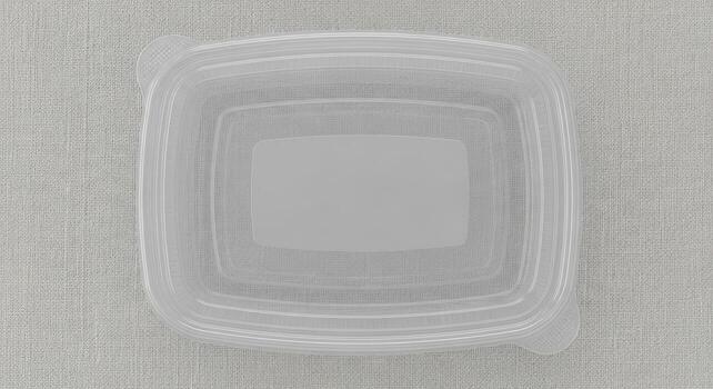 Clear plastic rectangular food container with a translucent lid, top view on a neutral textured background photo