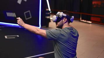 Man fully immersed in VR shooter game at virtual reality lounge. Wearing headset and motion controllers for deep 3D spatial engagement in competitive gameplay. video