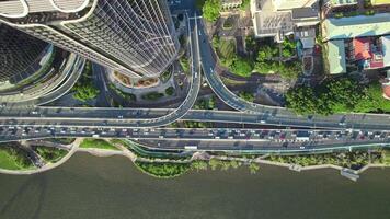 een verbijsterend antenne visie van een modern stad met een complex snelweg uitwisseling omringd door wolkenkrabbers, groen, en een waterkant. de verkeer stromen Aan de meerdere niveaus wegen video