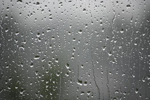 Raindrops cascade down a window pane, creating a beautiful, textured backdrop of nature's elements. photo