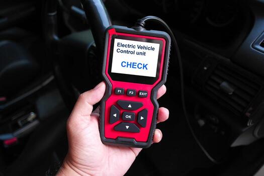 Hand holding an OBD2 scanner device for electric vehicle diagnostics, displaying Electric Vehicle Control Unit Check, used for system testing and troubleshooting EV performance photo