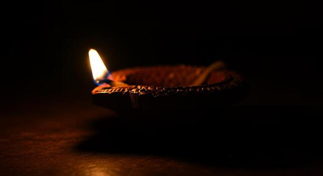 Macro Shot of Lit Diya Lamp with Warm Flame in Dark Room photo