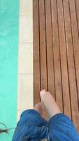 Close-up of bare feet resting at the edge of a sparkling pool on a bright sunny day, capturing the essence of relaxation and summer vibes, perfect for a vacation mood, enjoying leisure time and warm video