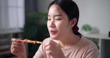 palmare sparo, sorridente asiatico donna godendo delizioso barbecue nel un' accogliente cenare camera. fatti in casa cibo. mangiare con rilassamento video