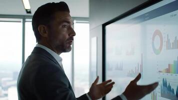 attività commerciale presentazione con fiducioso esecutivo puntamento per colorato grafici e grafici visualizzazione positivo prestazione dati nel un' moderno ufficio sala riunioni. video