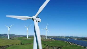 vento turbine generando pulito energia nel un' verde campo con chiaro blu cielo che rappresentano sostenibile energia soluzioni per un' meglio ambiente video