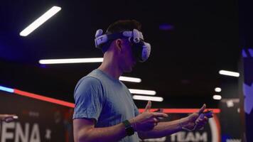 hombre en vr auriculares con palancas de mando activamente atractivo en virtual espacio mientras ajustando juego programa ajustes. vitrinas inmersivo tecnología interacción. video