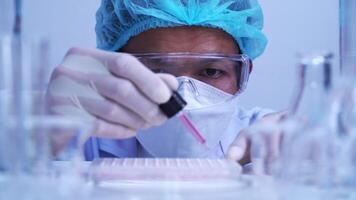 en man forskare dropp biokemisk lösning i till mikroplatta för dna analys. video