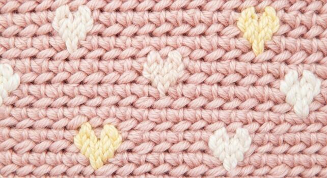 Hand knitted pink wool background with white and yellow heart patterns photo