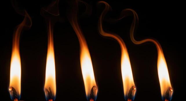 Close up of five burning matchsticks with smoke on a dark black background photo