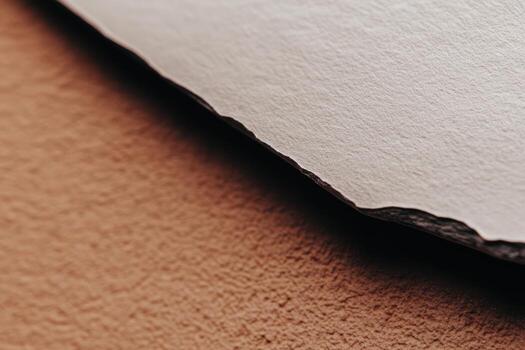 Textured paper edges on a warm brown surface during daylight photo