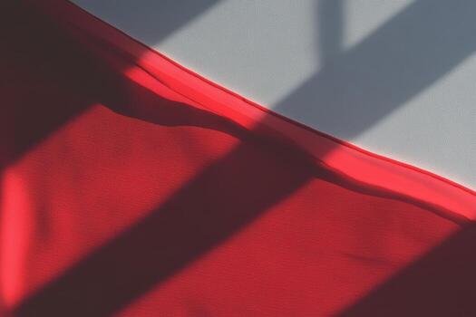 Red fabric drapes elegantly under soft morning light casting shadows photo