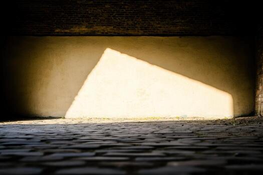 Light creates geometric shapes on a cobblestone surface in an old building photo
